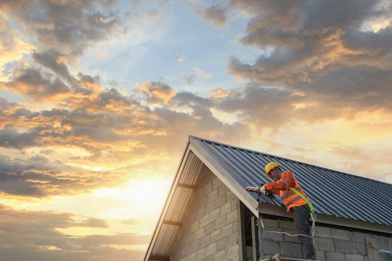 Roofing workers inspect exposed roof decking beside removed shingles on a residential home.